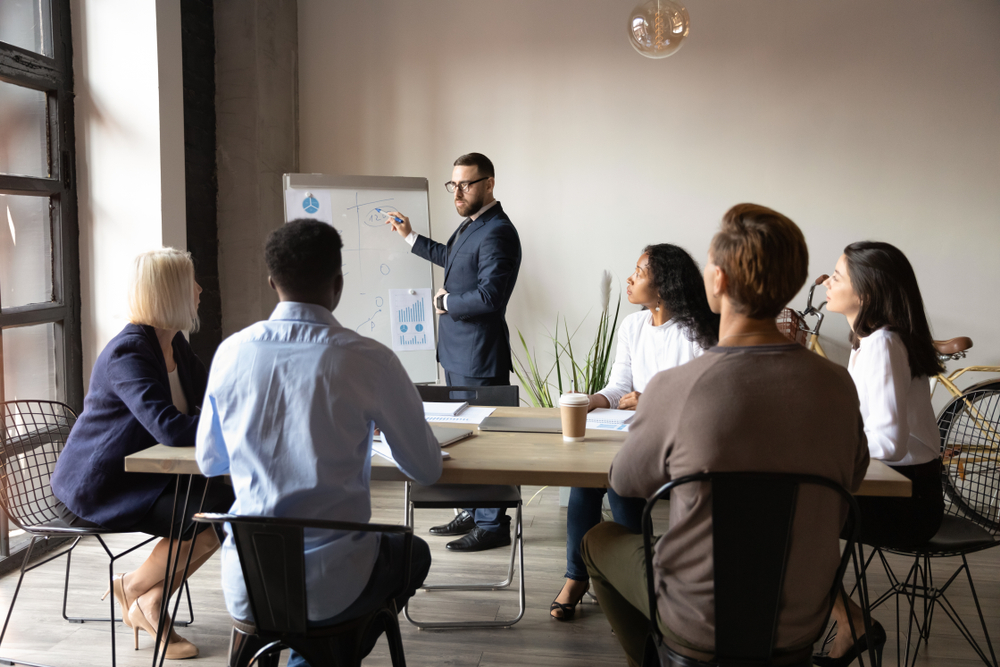 Man presents information on a white board to a group of people